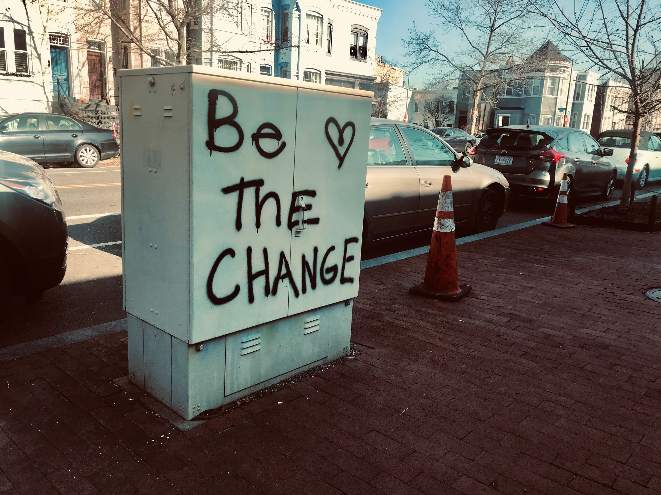 Painted words on a street utility box read: Be the change